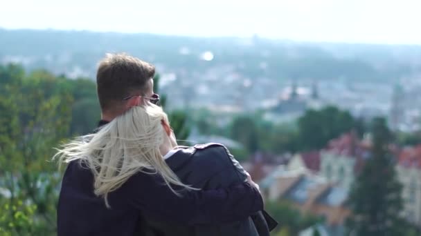 Pareja joven abrazándose disfrutando de la vista de la ciudad — Vídeos de Stock