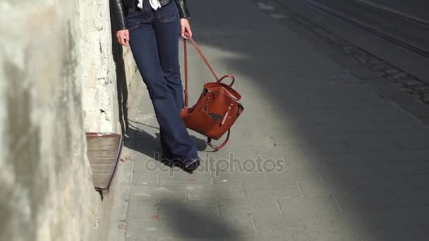 Menina loira bonita de pé perto da parede velha, segurando seu saco marrom — Vídeo de Stock