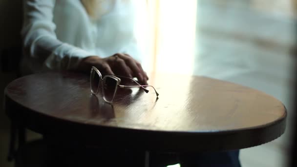 Γυαλιά ηλίου στο τραπέζι των διαπραγματεύσεων στο πλαίσιο της ένα μεγάλο παράθυρο σε ένα Cafe — Αρχείο Βίντεο