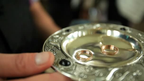 Homme tient plaque d'argent avec des alliances dans l'eau 