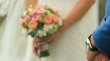 Gelin arka plan üzerinde duruyor iken damat elleri bir arada tutan şey