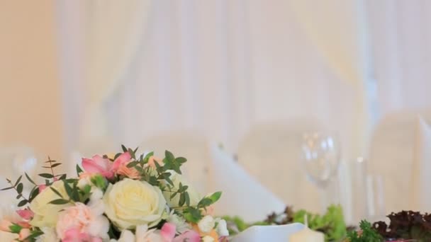 Pared decorada con guirnaldas de flores y cortinas blancas detrás de la mesa — Vídeos de Stock