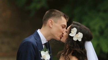 Uzun boylu damat beyaz orkide gelin saçında öper.