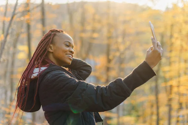 Selfie portrét roztomilé dívky v podzimním parku. Africká žena s úsměvem — Stock fotografie