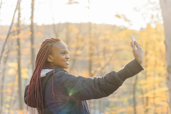 Linda chica atractiva haciendo selfie en el parque de otoño. Mujer africana sonriendo — Foto de Stock
