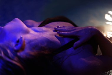 Güzel kız Spa fotoğrafını yan yukarıya kapatın. Çekici eğrileri ışık şaşırtıcı. Güzel kadın elini boynuna koy.
