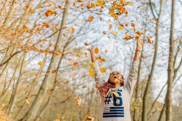 Menina bonita atraente feliz que joga com folhas, apreciando o dia quente do outono no parque. Divirta-se no outono — Fotografia de Stock