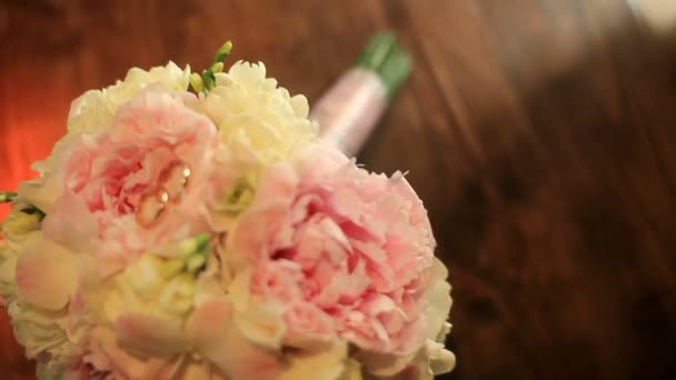 Свадебные кольца лежат на великолепном розовом букете — стоковое видео