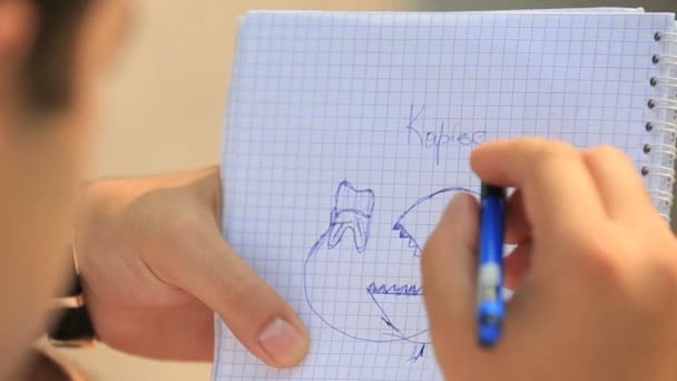 Frau malt Karies in ihr Notizbuch — Stockvideo