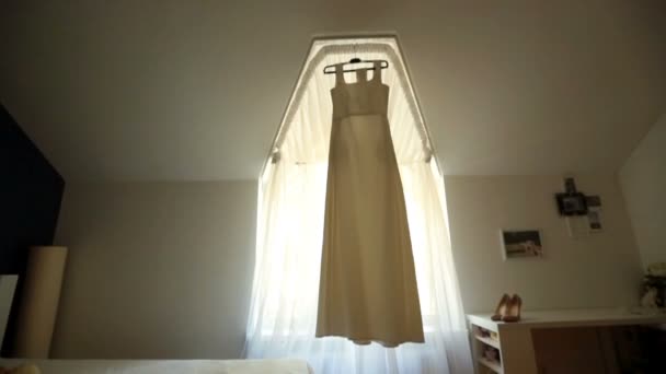 Wedding dress hangs before tall window — Stock Video