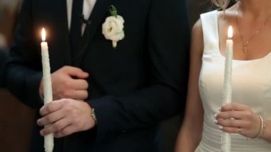 Yeni evliler kendilerini beyaz yanan mum tutan çapraz