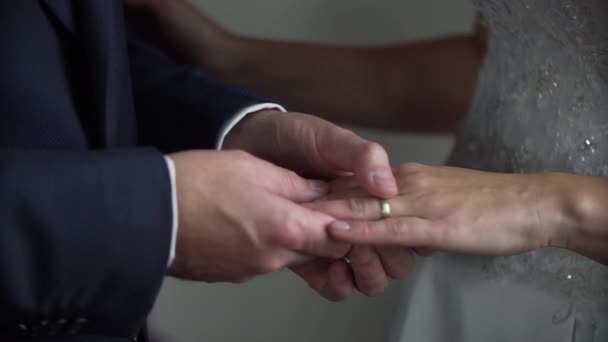 Groom em terno azul coloca anel de casamento em noivas mão macia — Vídeo de Stock