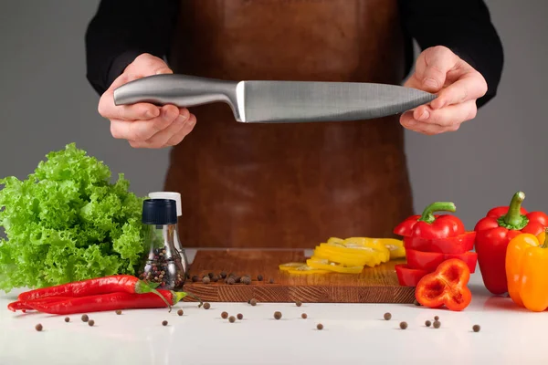 Σεφ κρατώντας ένα μαχαίρι στα χέρια του παραπάνω κοπής doard με φέτες πιπεριές — Φωτογραφία Αρχείου