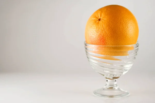Rijpe oranje in een glazen kom op witte achtergrond — Stockfoto