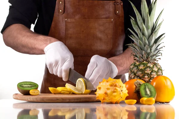 Cutting lemon into slices. Chef in white gloves. Assorted fruits