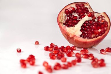 Yarısı nar beyaz zemin üzerinde. Nar tohumları dağınık ona yüzey