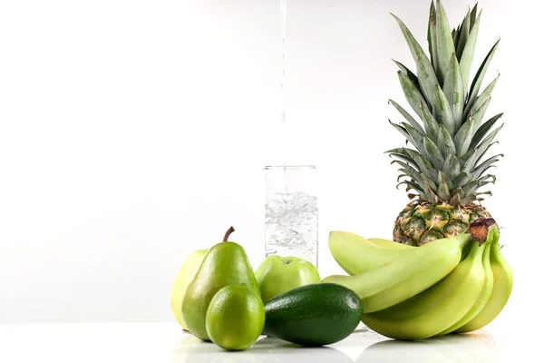Fruit op een witte achtergrond. Gieten van water in een glas. — Stockfoto