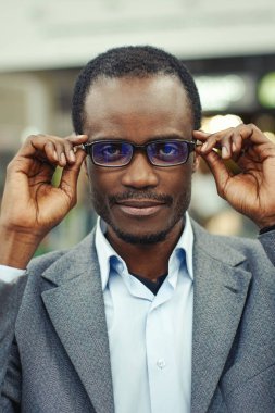 Yakışıklı afro Amerikalı adam şık giysiler ve kameraya bakarak ve gülümseyen bardakları