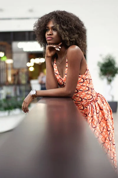 Hübsche junge Afro-Frau, die am Geländer steht. schöne lockige Haare und dunkle, glänzende Haut. — Stockfoto