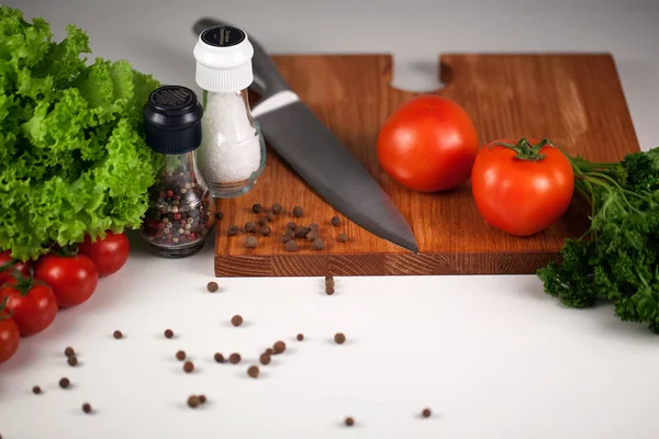 Powierzchnia robocza zbliżenie z drewnianą deską do krojenia, szefów kuchni nóż i warzywa — Zdjęcie stockowe