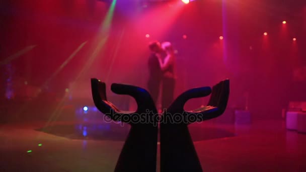 La estatuilla de manos en el club nocturno y la pareja de besos en el fondo — Vídeo de stock