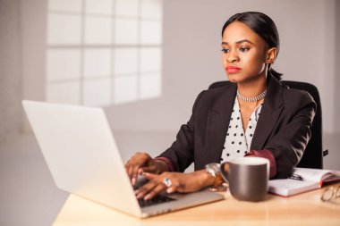 Onu laptop ofisteki çalımakta koyu parlak tenli güzel iş kadını