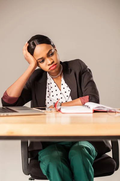 Mujer de negocios aburrida sentada junto a la mesa con herramientas de oficina . —  Fotos de Stock