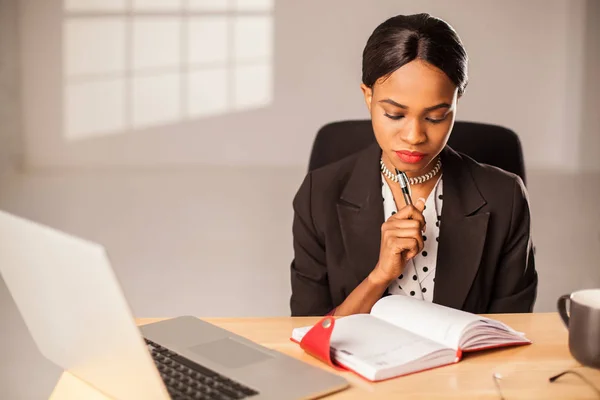 Doordachte zakenvrouw lezen iets in haar notitieblok. Vrouw zitten op kantoor. — Stockfoto