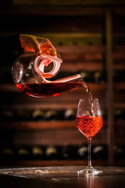 Wine pouring into a glass from figured carafe. Composition placed in a wine vault. — Stock Photo, Image