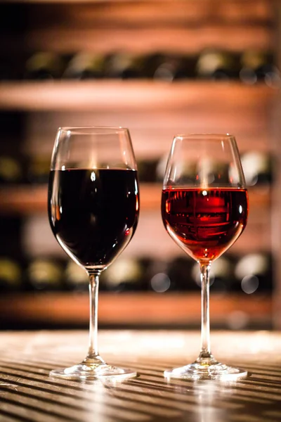 Tiro vertical de dois copos de vinho na mesa de madeira. Vinho localização vaul . — Fotografia de Stock