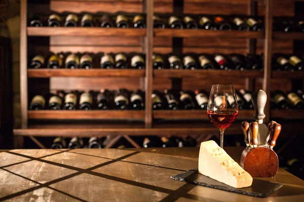 Композиция в винном хранилище. Бокал вина, сыр и аксессуары на деревянном столе . — стоковое фото