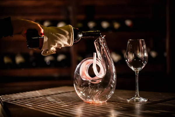 Wine pouring from a bottle into carafe. Wine vault location. — Stock Photo, Image