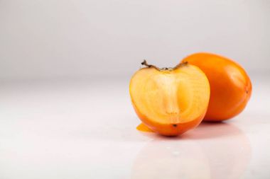 İki hurma veya beyaz bir arka plan üzerinde kaki meyve. Bir meyve ikiye kesilmiş