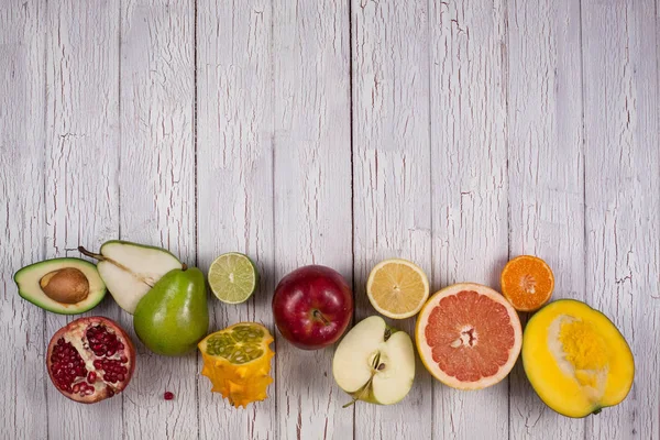 Fruits cut into halves making a row and placed on a wooden board