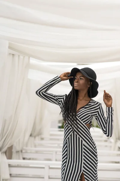 Porträt einer schönen afroamerikanischen jungen Frau, die mit erhobenen Händen ihren Hut hält. — Stockfoto