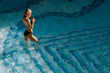 seksi kadın güneş tabaklanmış ince ve düzgün vücut üzerinde siyah Bikini yüzme havuzunda poz
