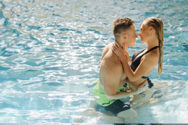 Öpüşme ve yüzme havuzunda sarılma genç, seksi çift. Tatil tropikal ülke, caribbean ya Hawaii hayal ediyorum. Otelde Yüzme Havuzu