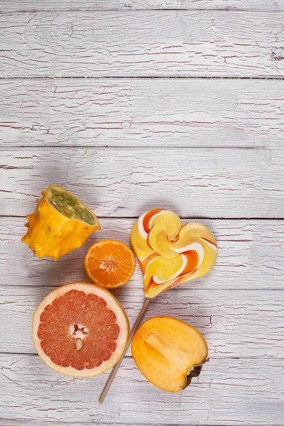 Compositie van vers fruit en zoete lolly geplaatst op een licht houten bord — Stockfoto