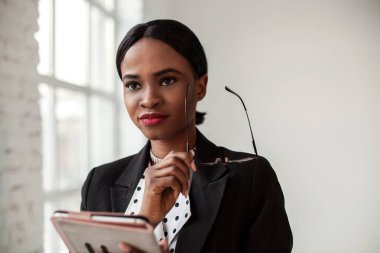 Düşünceli afroamerican işkadını tablet ve glassen onun elinde tutan.