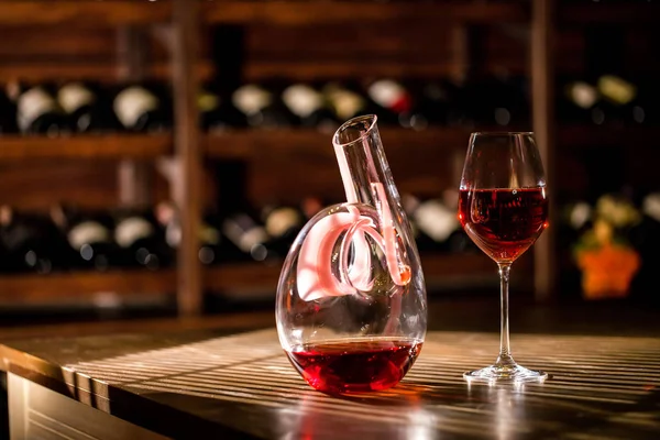 Composition of wine carafe and glass placed on the table in a wine vault.