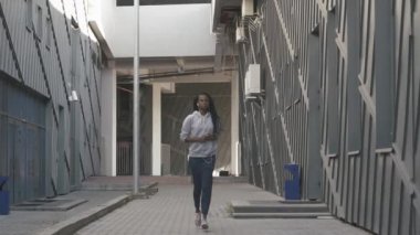 Binalar boyunca athlatic Afro-Amerikan kadın koşu. Model müzik