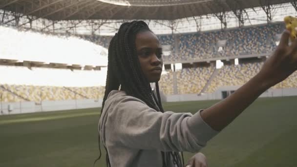 El retrato de la joven afro-americana con el pelo castaño oscuro tomando selfie en el estadio deportivo — Vídeo de stock