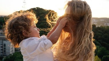 Anneler saçlarıyla oynarken küçük oğlu. Güzel sarışın kadın.