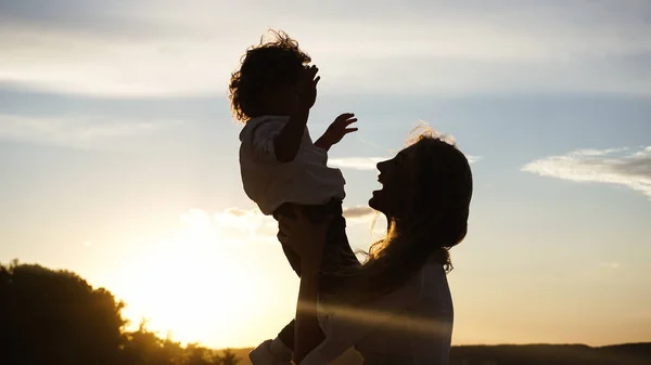 Silhueta de uma jovem mãe com seu filho . — Fotografia de Stock