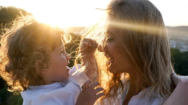 Lycklig mamma och hennes lilla barn. Barn leker med mödrar hår, — Stockfoto