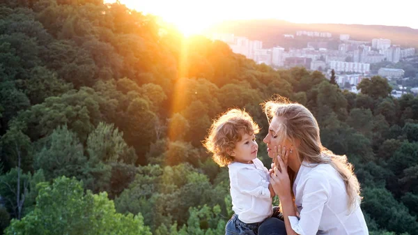 Время заката. Мама и ее маленькое солнце играют вместе. Вид на город и природу . — стоковое фото