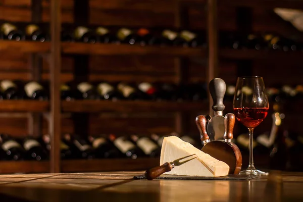 Composizione nel caveau del vino. Bicchiere da vino, formaggio e accessori posti su un tavolo di legno . — Foto Stock