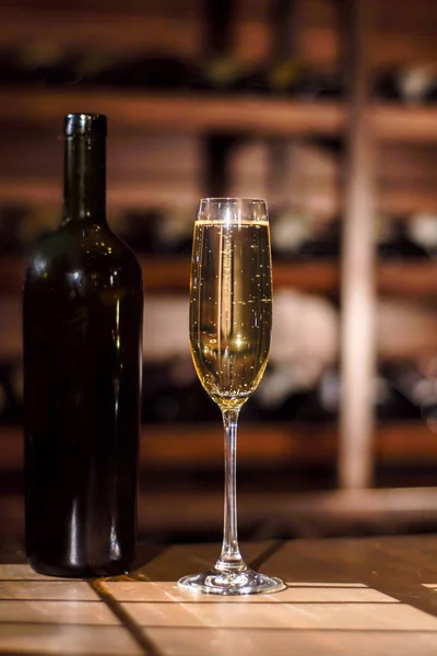 Bottiglia e bicchiere di champagne su un tavolo di legno in una pentola da vino . — Foto Stock