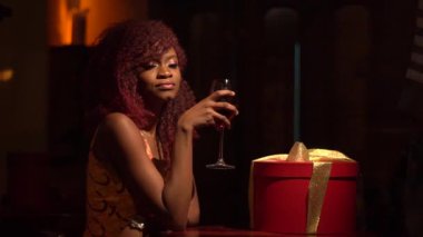 Kırmızı kıvırcık saçlı olsa da pencereden bakarak ve samimi kafede kırmızı şarap içme Afro-Amerikan kız