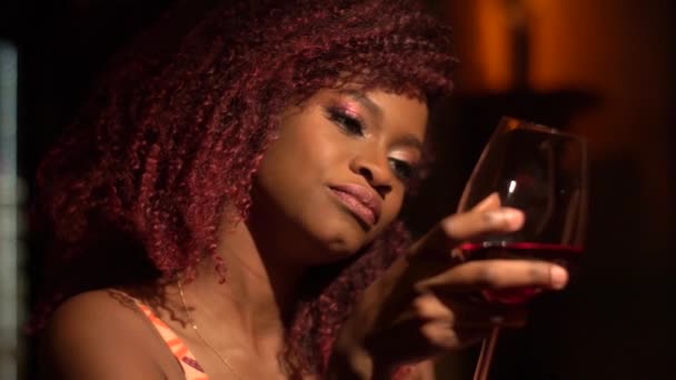 Муди афро-американка держит бокал, проводит вечер в кафе в одиночестве — стоковое видео